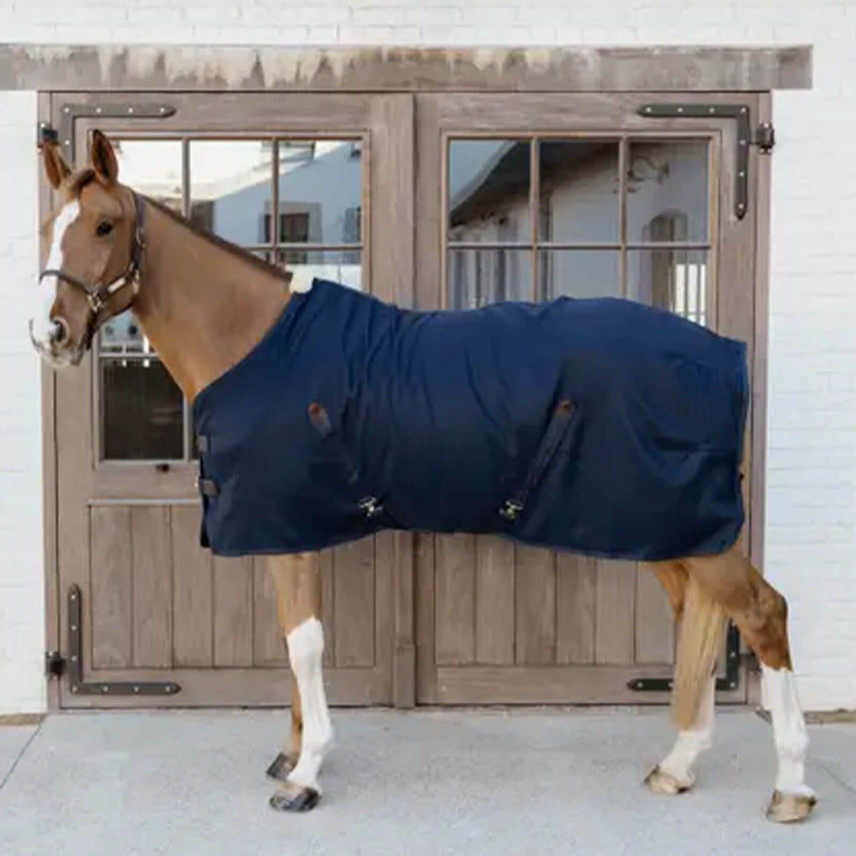 Kentucky Horsewear Stalldecke 0g Classic Stalldecke, Dunkelblau, Pferd trägt die Decke vor einer Stalltür.