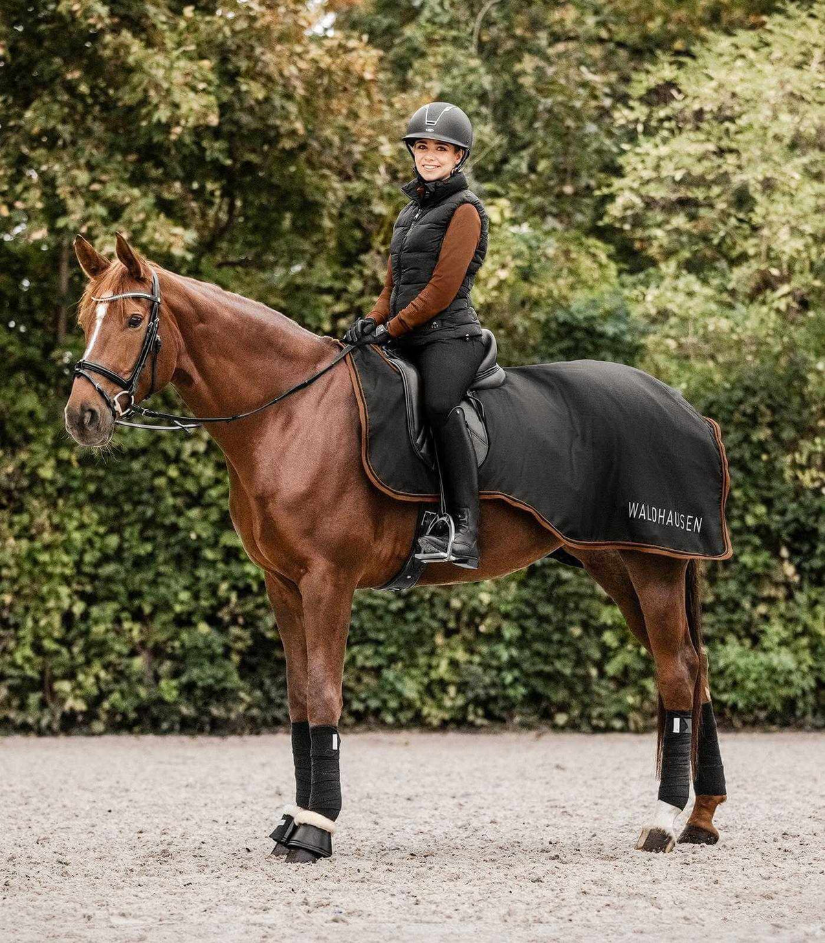 Waldhausen Regen-Ausreitdecke 50g Perth, Schwarz, Reiterin auf Pferd im Gelände.