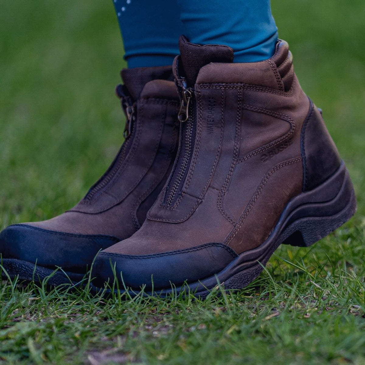 Reit- und Stallschuh Zip It Wasserdicht Outdoorschuh, braun, an einer Person im Gras.