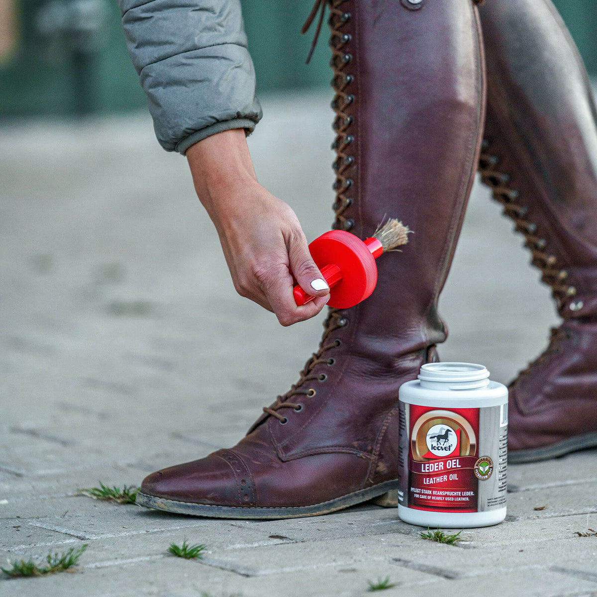 leovet Leder Oel Lederpflege, Produkt allein, Person trägt Lederstiefel und trägt Öl auf.