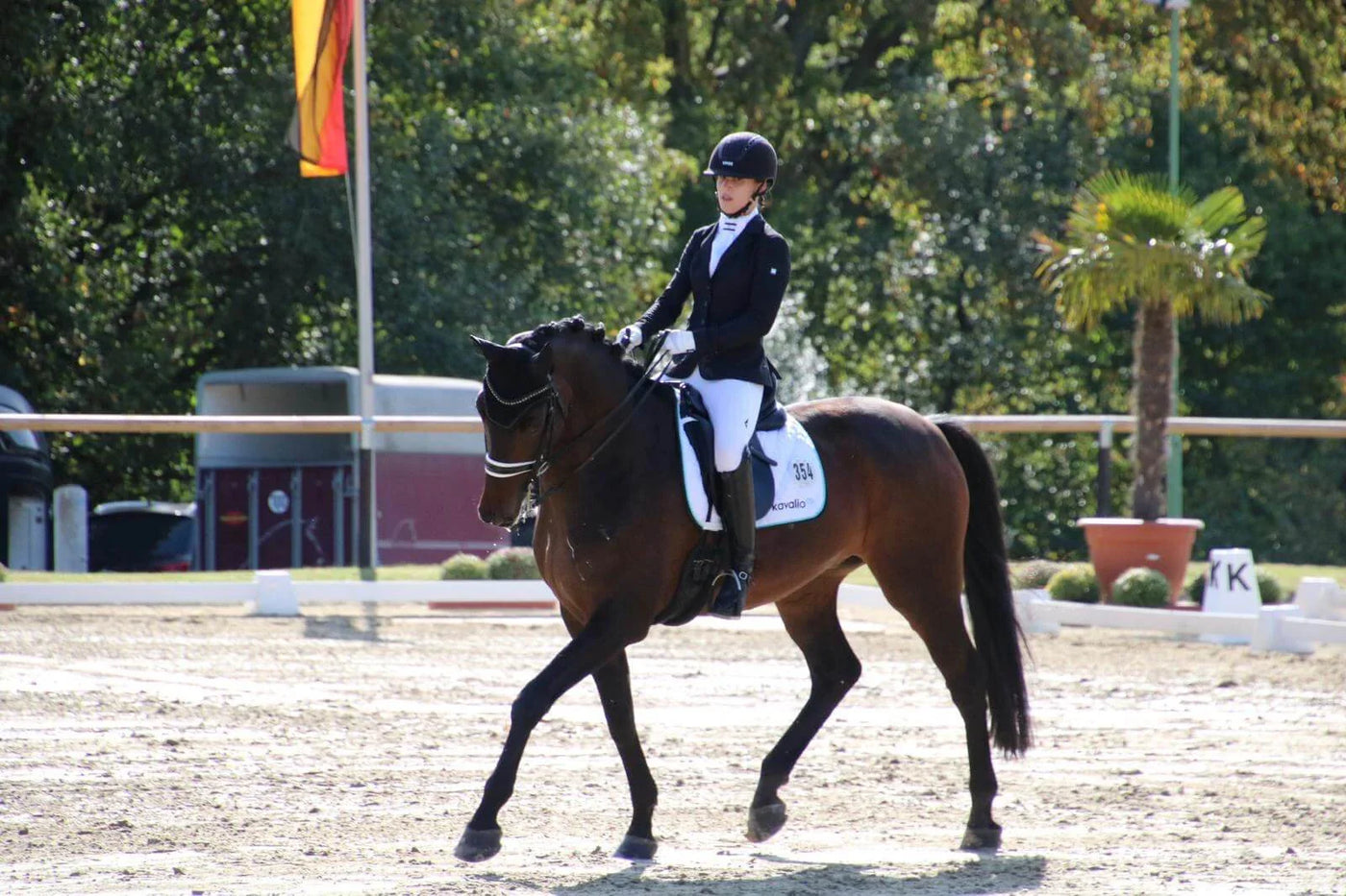 Reiterin auf braunem Pferd im Dressurviereck, TURNIER ROUTINE von kavalio TEAMREITERIN Chiara.