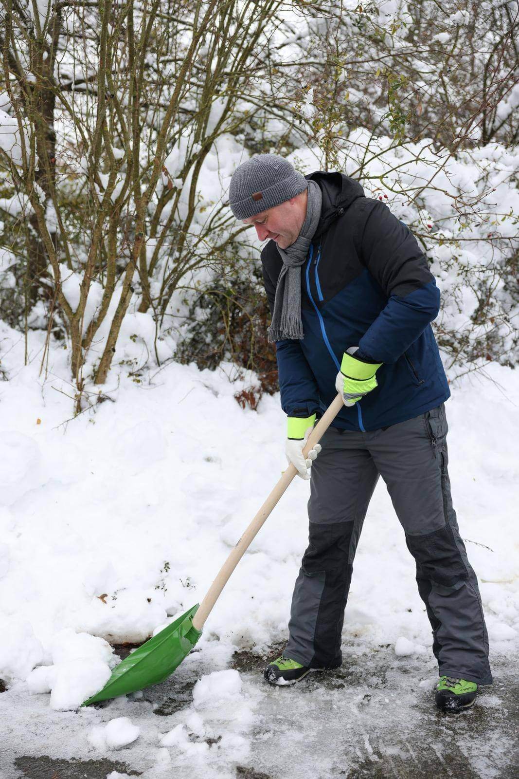 KERBL Schnee- und Getreideschaufel ohne Stiel, Grün, Person schaufelt Schnee im Freien.