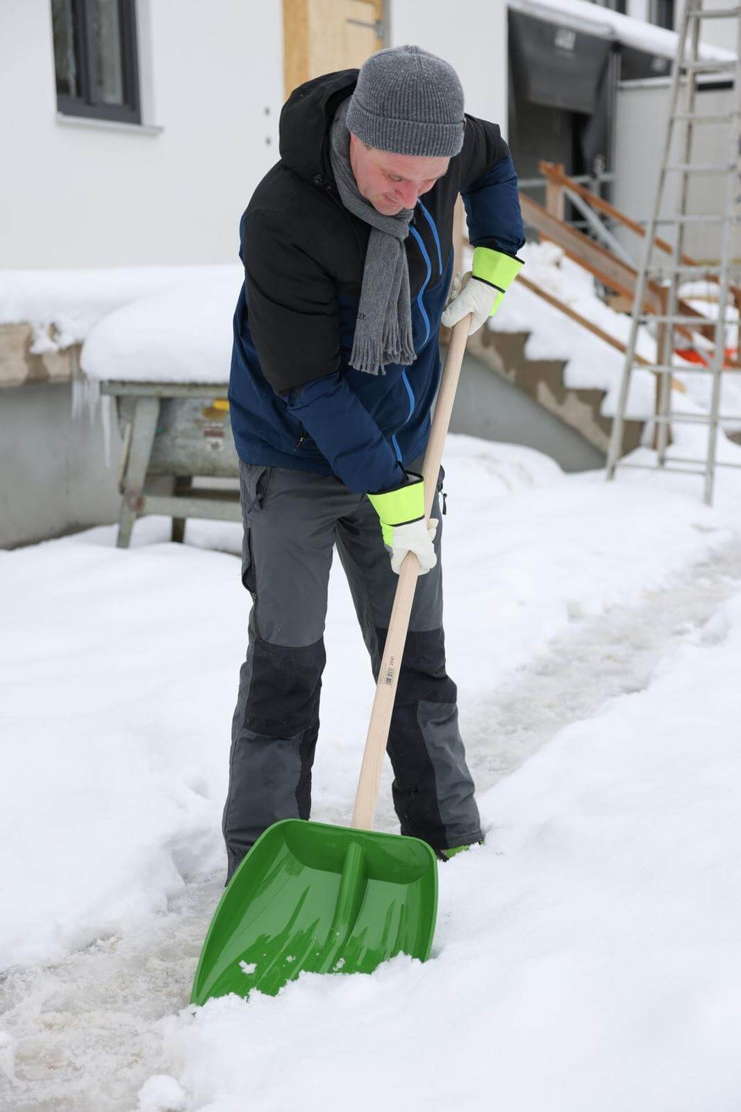 KERBL Schnee- und Getreideschaufel ohne Stiel, Grün, Person schaufelt Schnee.