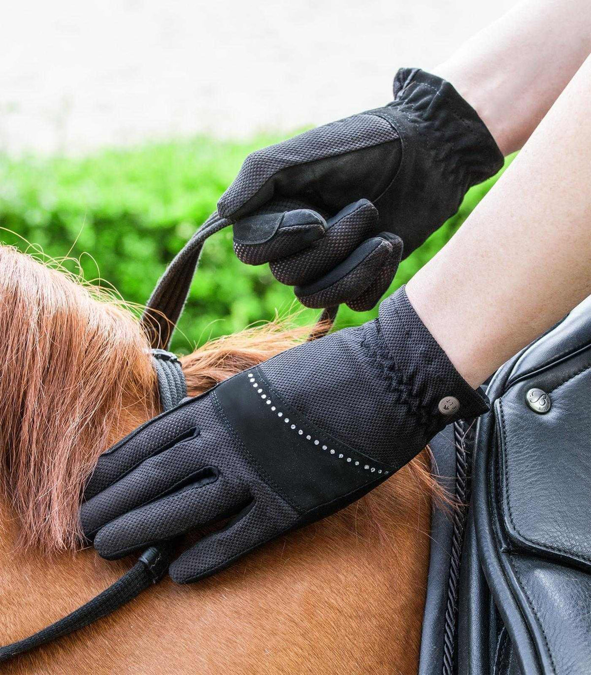 Reithandschuh Arosa, Schwarz, Reiterin mit Handschuhen am Pferd.
