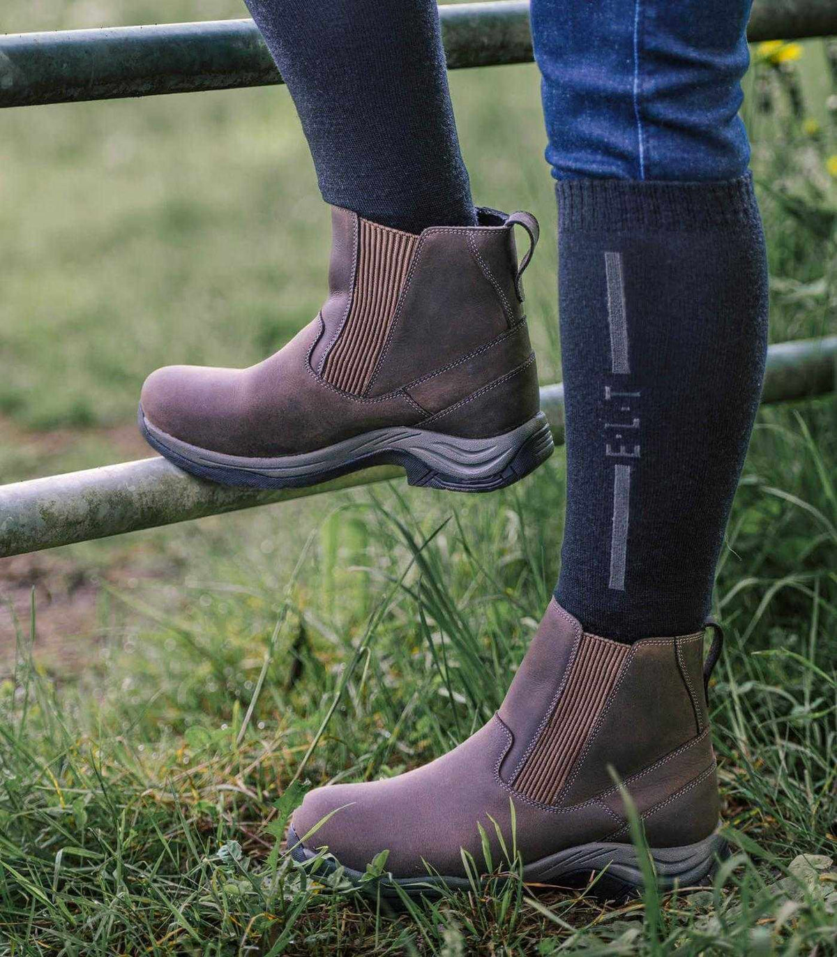E.L.T Reitsocken Performance Schwarz/Tiefblau, Person trägt Reitstiefel im Freien.
