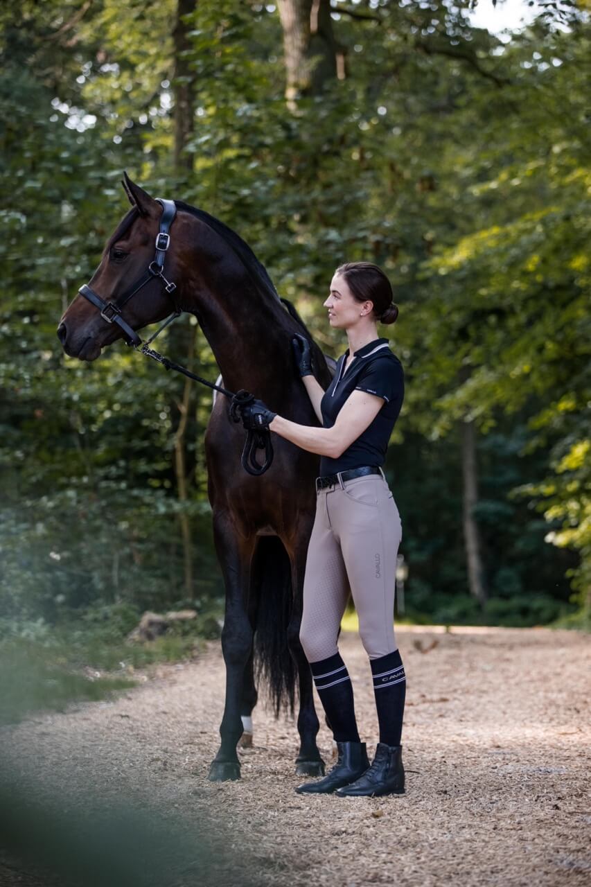 Cavallo Poloshirt CAVALPIQUE Shirt, Schwarz, Reiterin am Pferd im Freien.