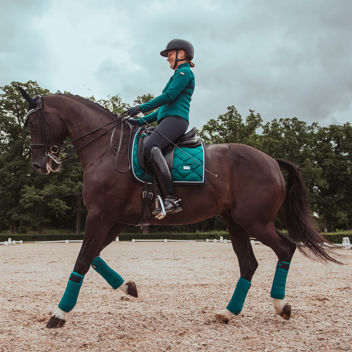 Equestrian Stockholm Bandagen Emerald, Emerald, Reiterin auf Pferd im Dressurviereck.